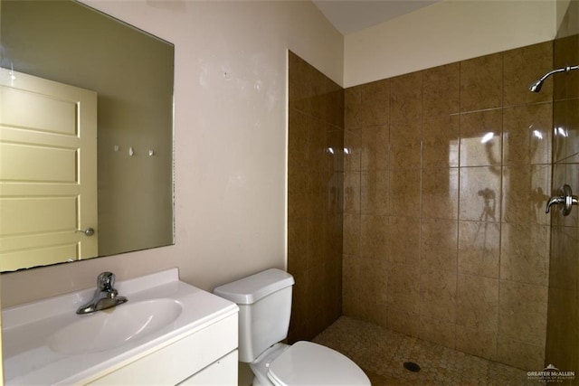 bathroom with toilet, vanity, and tiled shower