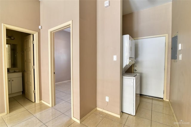 laundry room with light tile patterned floors, electric panel, and stacked washer and dryer