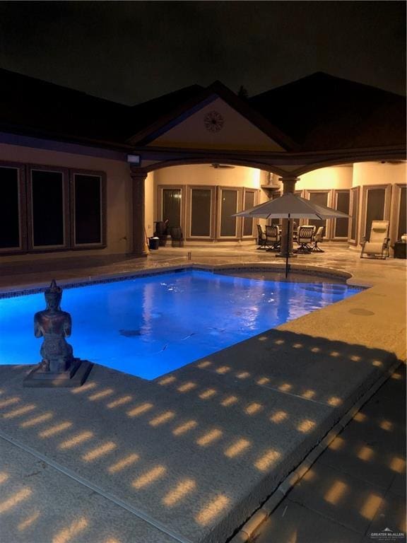 pool at night with a patio area