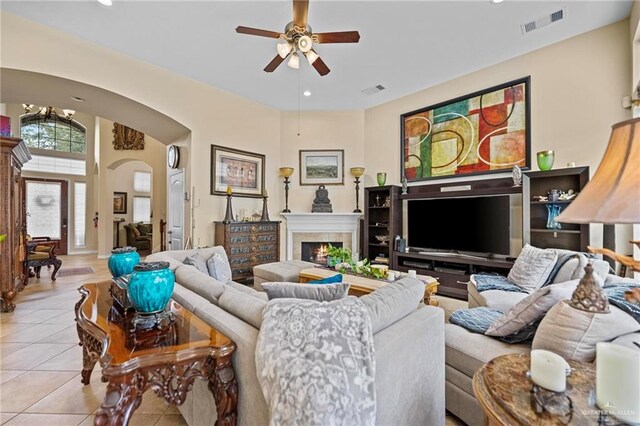 tiled living room featuring a tile fireplace and ceiling fan