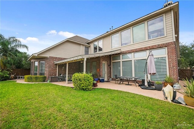 rear view of house featuring a lawn and a patio