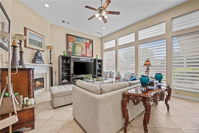 living room featuring a tile fireplace, ceiling fan, and light tile patterned floors