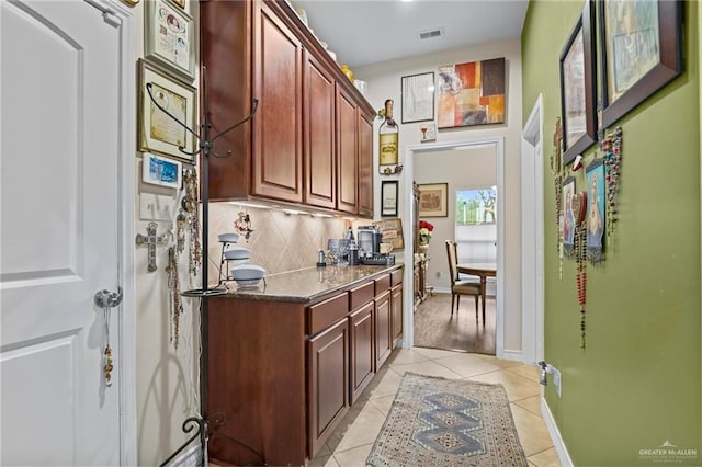 kitchen with backsplash, dark stone countertops, and light tile patterned floors