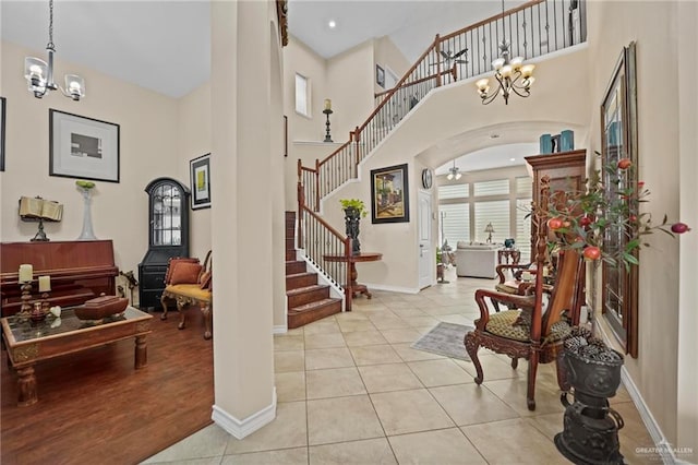 entrance foyer featuring ceiling fan with notable chandelier, a towering ceiling, and light tile patterned floors