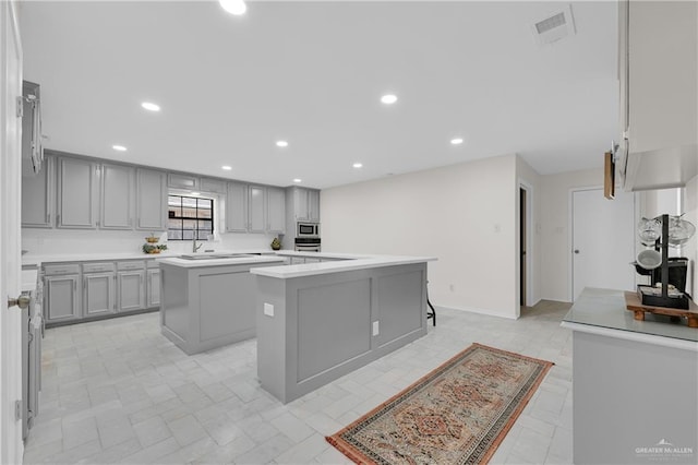 kitchen with visible vents, a kitchen island, gray cabinets, stainless steel appliances, and light countertops