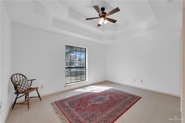 living area with light tile patterned flooring, a raised ceiling, a ceiling fan, and baseboards