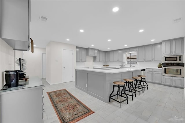 kitchen with gray cabinets, stainless steel appliances, light countertops, and recessed lighting