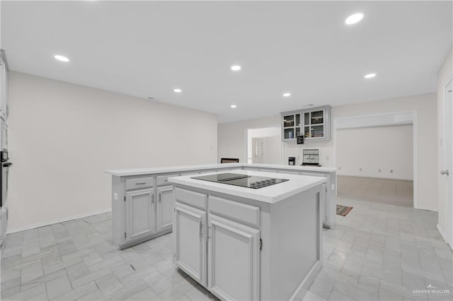 kitchen featuring black electric stovetop, recessed lighting, white cabinets, light countertops, and a center island