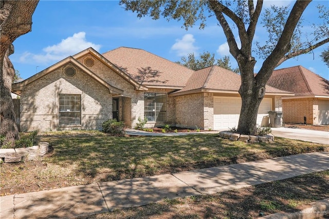 view of front of property featuring brick siding, a shingled roof, an attached garage, driveway, and a front lawn