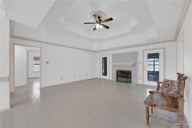 living room with a fireplace with flush hearth, baseboards, a raised ceiling, and a ceiling fan