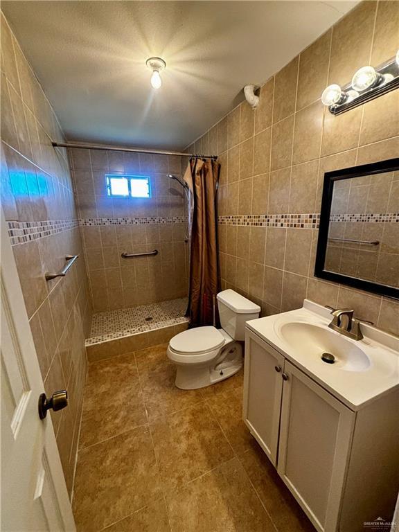 21732 Mile 17 Rd, Edinburg, TX 78541 - bathroom featuring tiled shower, tile patterned flooring, tile walls, toilet, and vanity
