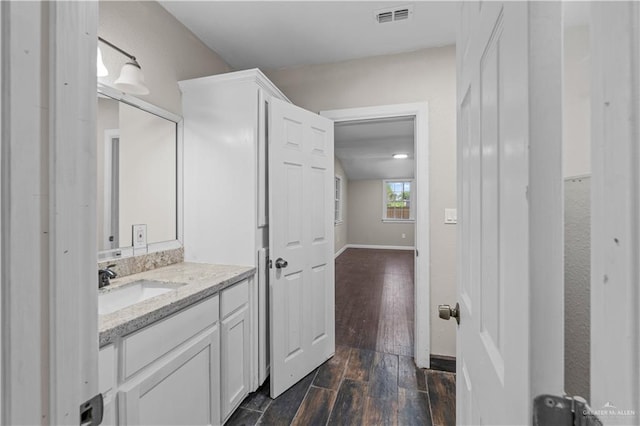 615 Iowa St, Mercedes, TX 78570 - bathroom with wood finished floors, vanity, baseboards, and visible vents