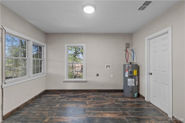615 Iowa St, Mercedes, TX 78570 - empty room featuring baseboards, visible vents, electric water heater, and wood finished floors