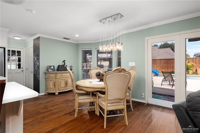 dining space with dark wood-style flooring, crown molding, and baseboards