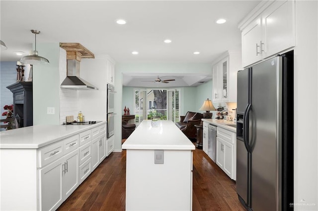 kitchen with a kitchen island, appliances with stainless steel finishes, open floor plan, dark wood-style flooring, and wall chimney range hood