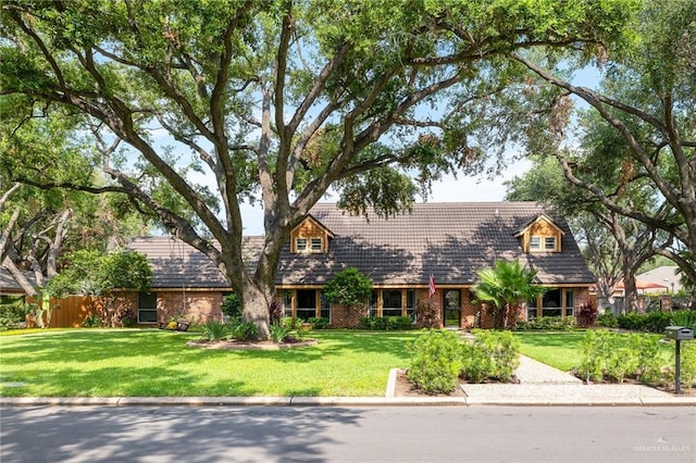 cape cod home with brick siding and a front yard