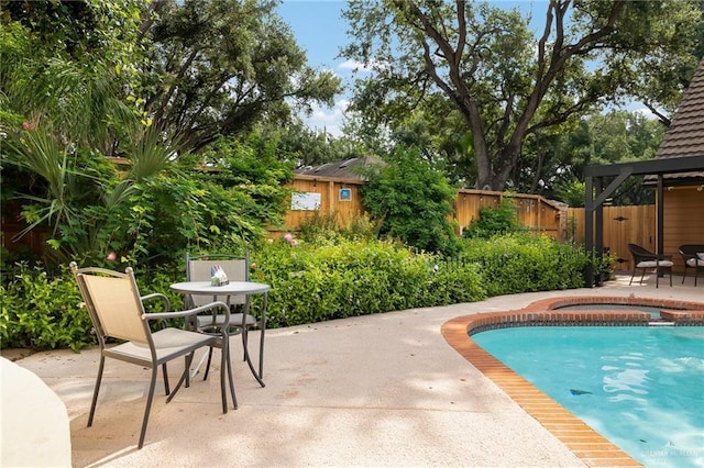 view of pool featuring a patio, fence, and a pool with connected hot tub