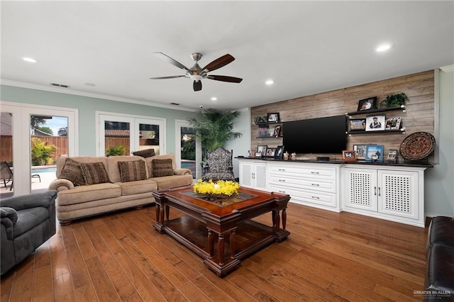 living area with recessed lighting, wood-type flooring, crown molding, and french doors