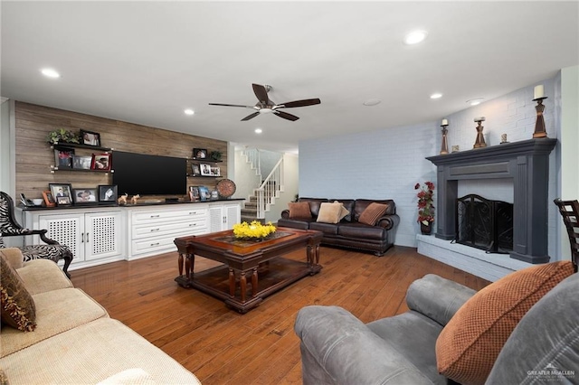 living room with a fireplace with raised hearth, stairway, wood finished floors, and recessed lighting