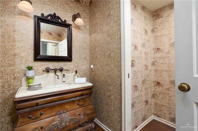 bathroom featuring baseboards, wood finished floors, and vanity