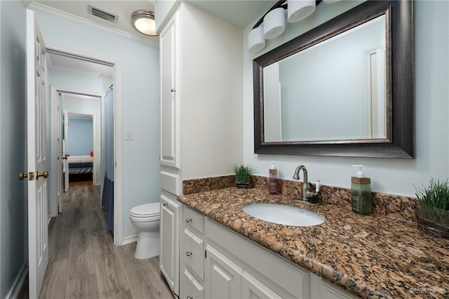 bathroom with visible vents, vanity, toilet, and wood finished floors