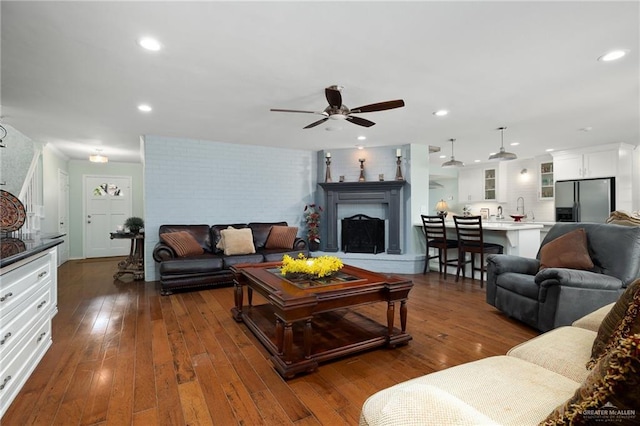 living area featuring a ceiling fan, recessed lighting, a fireplace with raised hearth, and dark wood finished floors