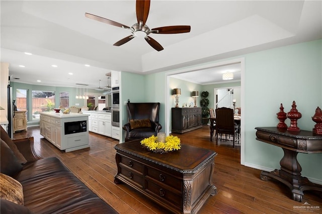 living area with baseboards, dark wood finished floors, a raised ceiling, ceiling fan, and recessed lighting