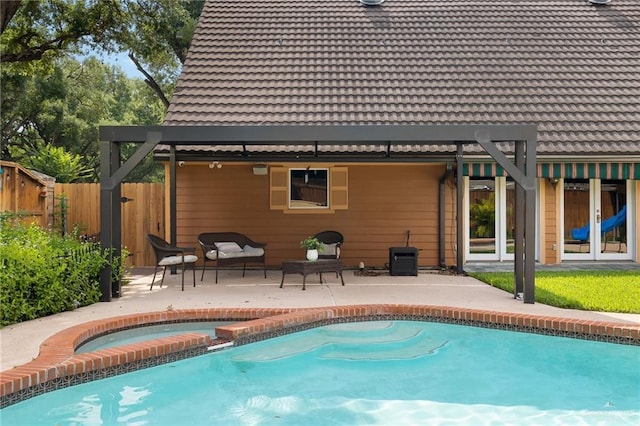 rear view of house with a tiled roof, a patio, fence, and a pool with connected hot tub