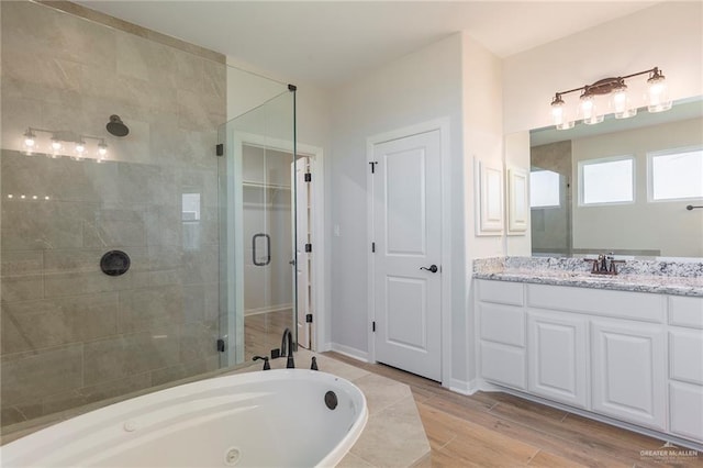 bathroom with vanity, a jetted tub, baseboards, wood finished floors, and a stall shower