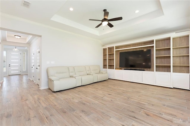 unfurnished living room featuring a ceiling fan, a tray ceiling, wood finished floors, and visible vents