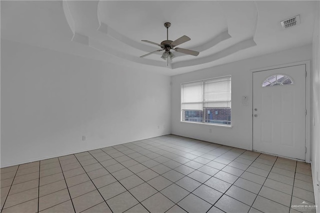 foyer featuring ceiling fan, light tile patterned floors, and a tray ceiling