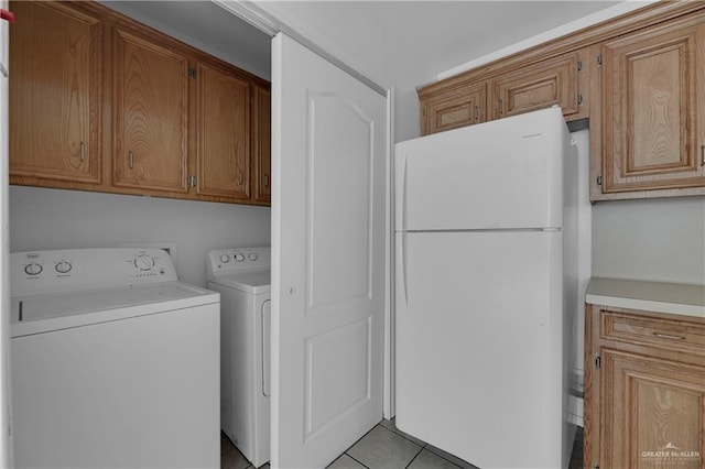 washroom featuring washing machine and dryer, light tile patterned floors, and cabinets