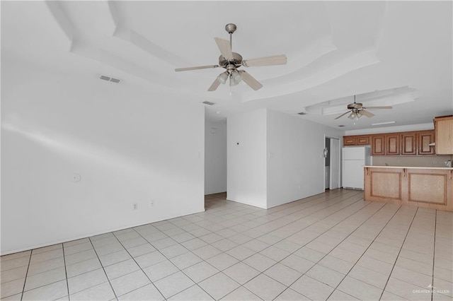 unfurnished living room featuring light tile patterned floors, a raised ceiling, and ceiling fan