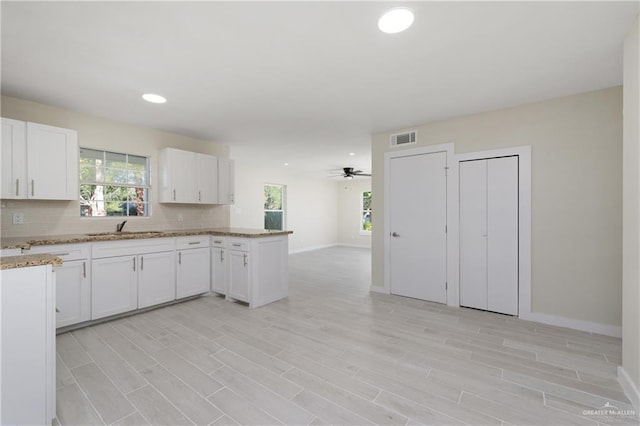 kitchen with white cabinets, backsplash, ceiling fan, and sink