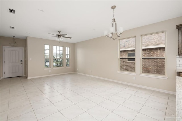 tiled empty room featuring ceiling fan with notable chandelier