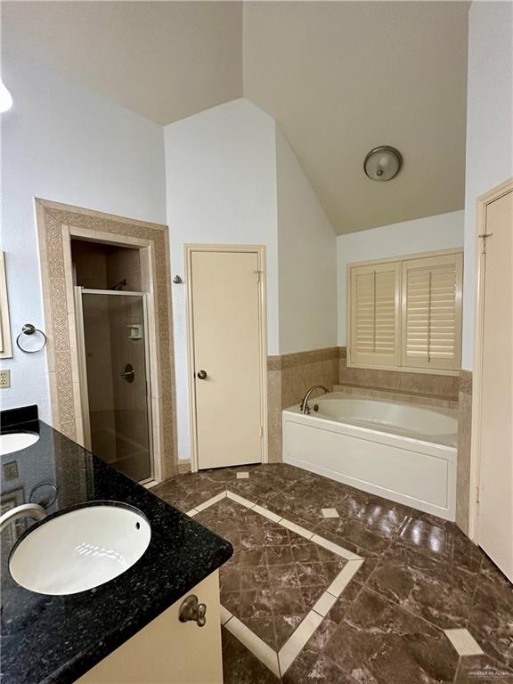 6200 N Cynthia St, Mcallen, TX 78504 - full bath featuring vanity, a garden tub, a stall shower, vaulted ceiling, and wainscoting