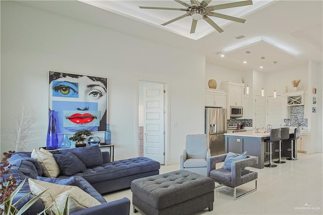 living room with visible vents, a high ceiling, and ceiling fan