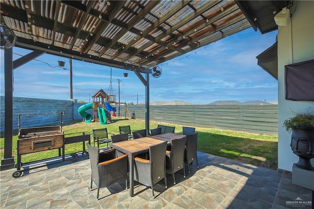 view of patio / terrace featuring outdoor dining space, playground community, and a fenced backyard