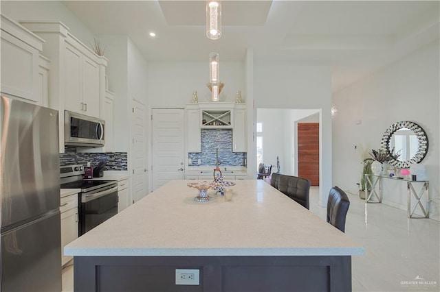 kitchen featuring decorative backsplash, light countertops, appliances with stainless steel finishes, and a center island