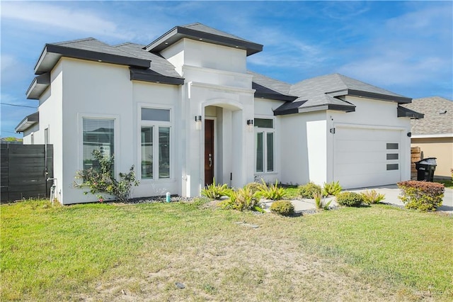 prairie-style home with stucco siding, an attached garage, a front lawn, and fence