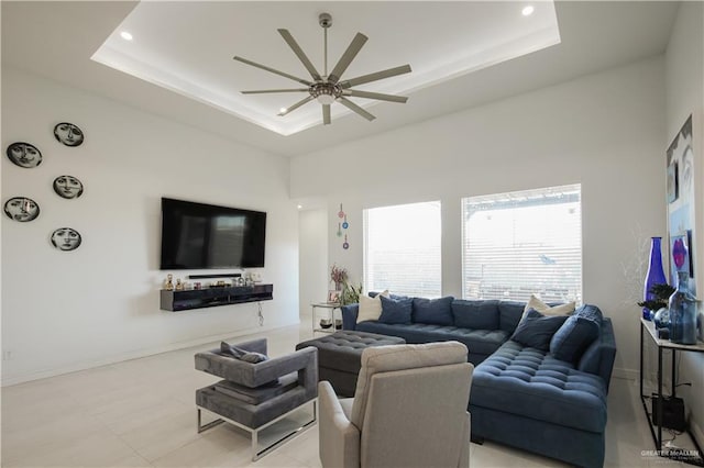 living room featuring a raised ceiling, recessed lighting, baseboards, and ceiling fan