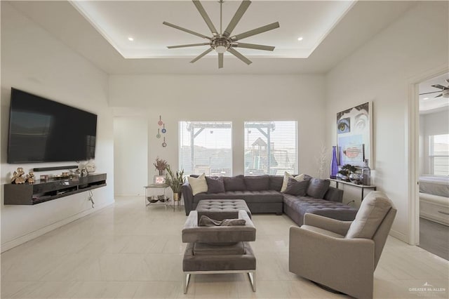 living area with a healthy amount of sunlight, a tray ceiling, and ceiling fan