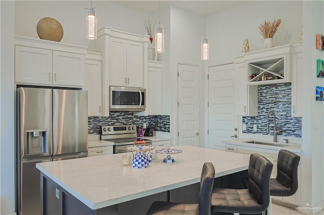 kitchen featuring a kitchen island, a sink, stainless steel appliances, light countertops, and a kitchen bar