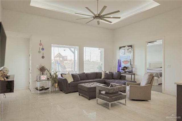 living room with a raised ceiling, baseboards, a towering ceiling, and ceiling fan