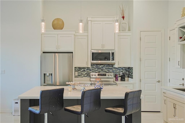 kitchen featuring decorative backsplash, white cabinets, and appliances with stainless steel finishes