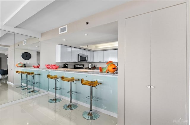 kitchen with tile patterned flooring, white cabinetry, and stainless steel appliances