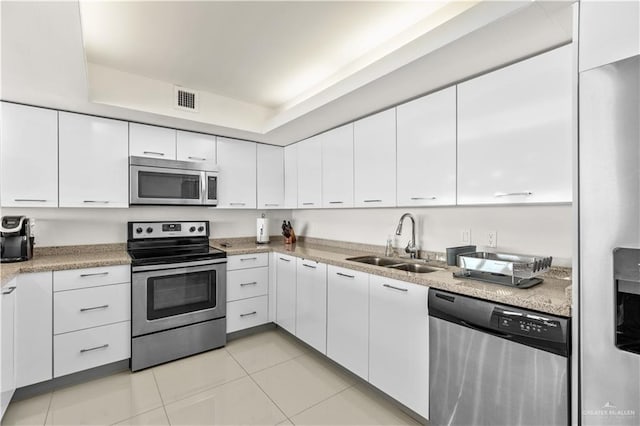 kitchen with sink, white cabinets, stainless steel appliances, and light tile patterned floors