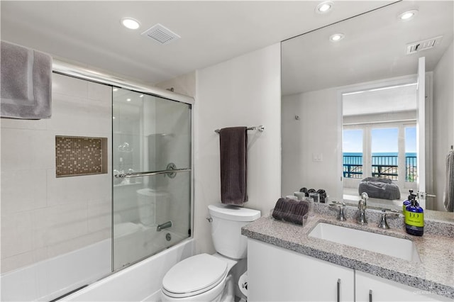 full bathroom with combined bath / shower with glass door, vanity, a water view, and toilet