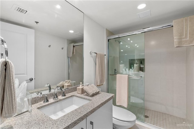 bathroom with toilet, vanity, and walk in shower