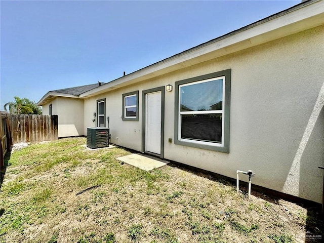 back of property with central AC unit and a lawn